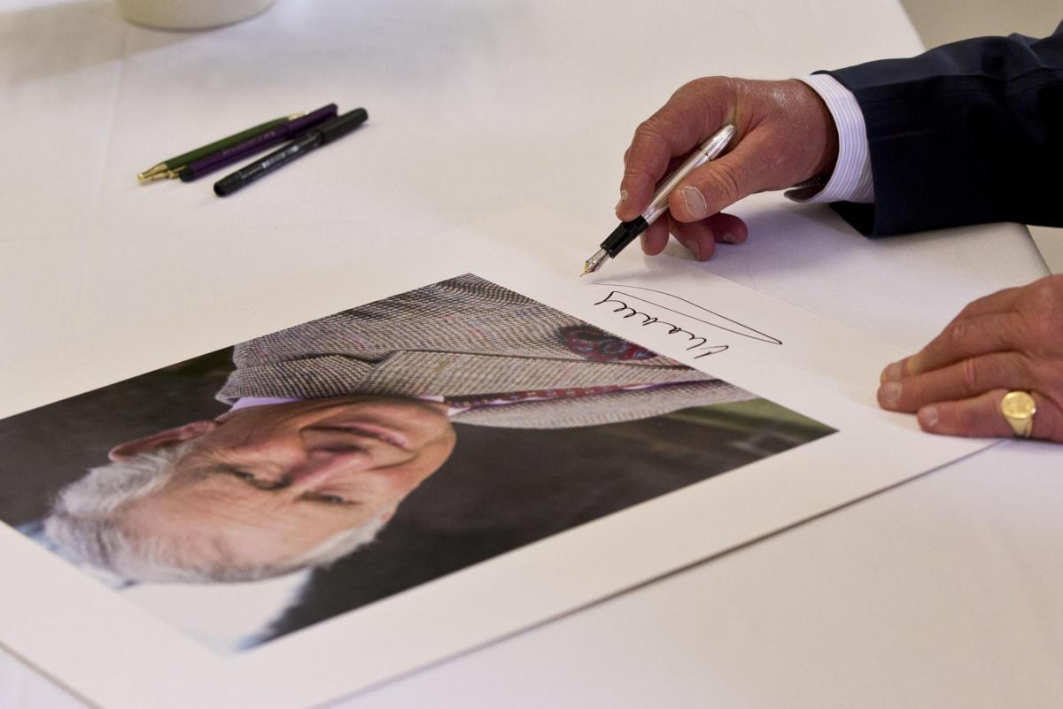 Prince Charles signs a picture of himself