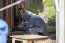 Police forensics officers in an alleyway at the back of properties on Darell Road in Kew. © PA
