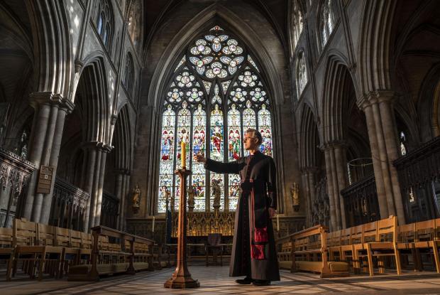 Richmond and Twickenham Times: Very Reverend John Dobson Dean of Ripon lights a candle to mark the second anniversary of the first national coronavirus lockdown at Ripon Cathedral, North Yorkshire, ahead of the National Day of Reflection on Wednesday (PA)