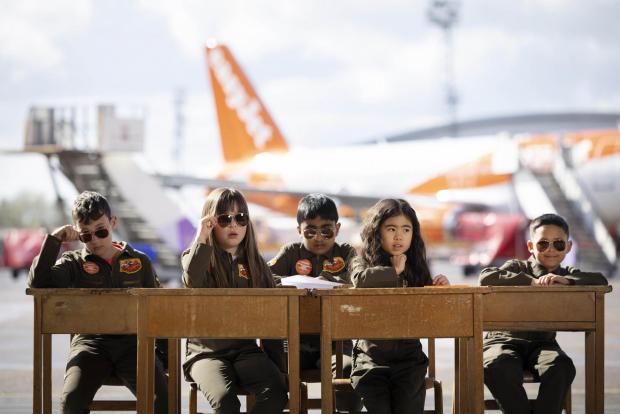 Richmond and Twickenham Times: Sam Bennett, aged 12, Olivia Joohee-Riddington, aged 9, Arjun Giri, aged 9, Rei Diec, aged 7 and Rico Jeerasinghe, aged 9 during filming of a parody of the movie Top Gun at Luton airport as part of easyJet's nextGen recruitment campaign. Credit: PA/easyJet