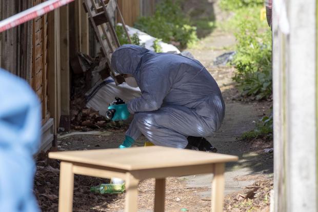 Police forensics officers in an alleyway at the back of properties on Darell Road in Kew. © PA